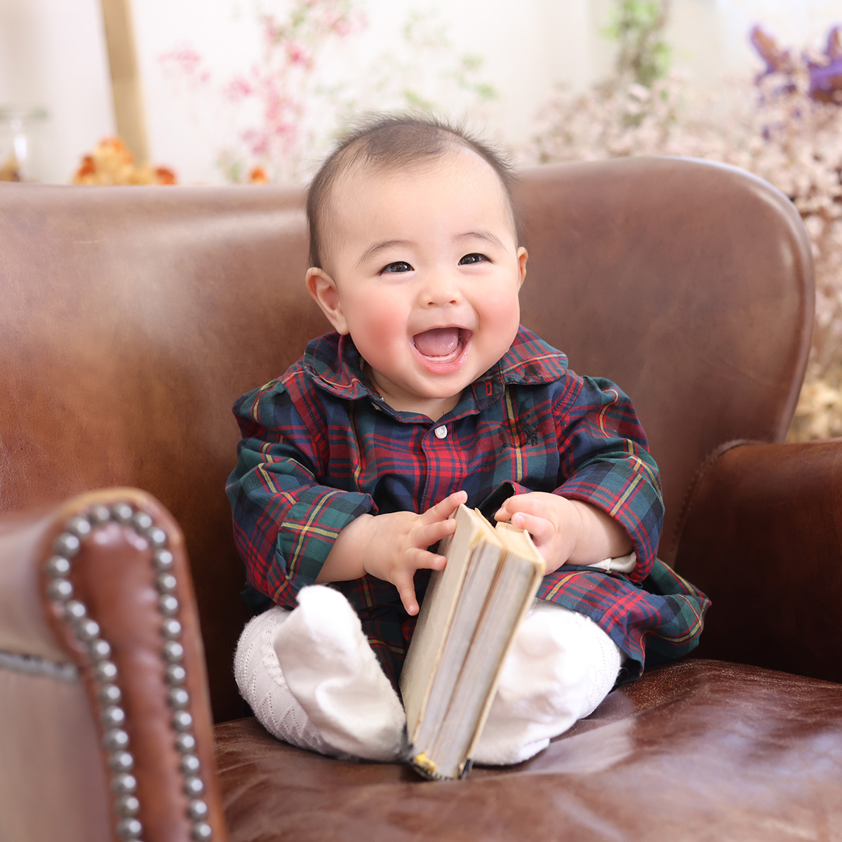 ハーフバースデーで、本を持って笑っている赤ちゃんの写真